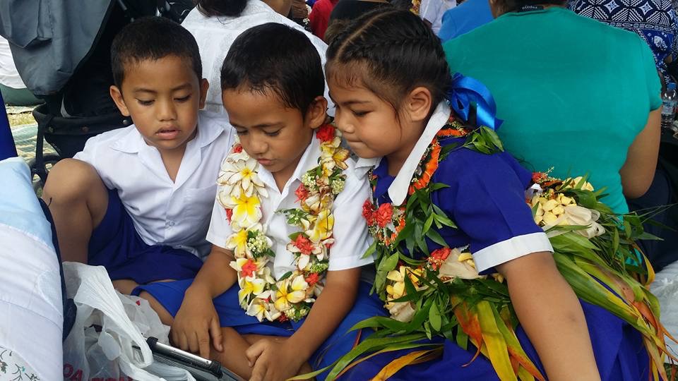 Tongan children with a device..